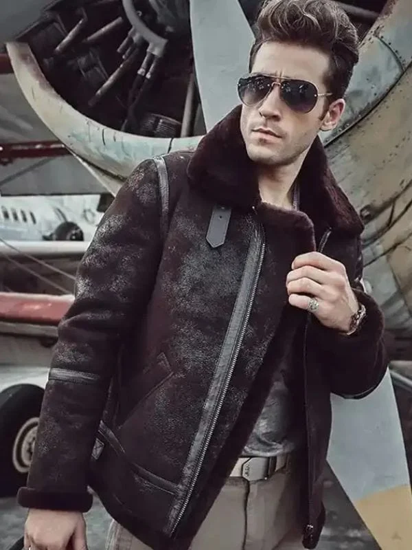 Model wearing Mens Distressed Dark Brown B3 Shearling Leather Jacket standing near vintage airplane