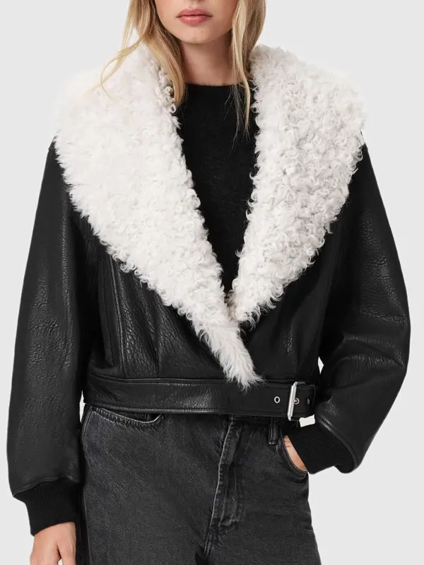 Front view of the black leather jacket with a prominent white shearling lapel collar and buckled waist belt. The Moment Lily McMenamy Black Leather Jacket